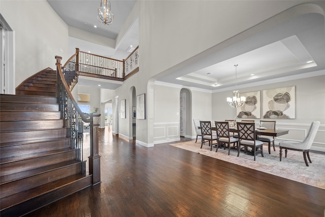 entrance foyer with a raised ceiling, ornamental molding, dark hardwood / wood-style floors, and a notable chandelier