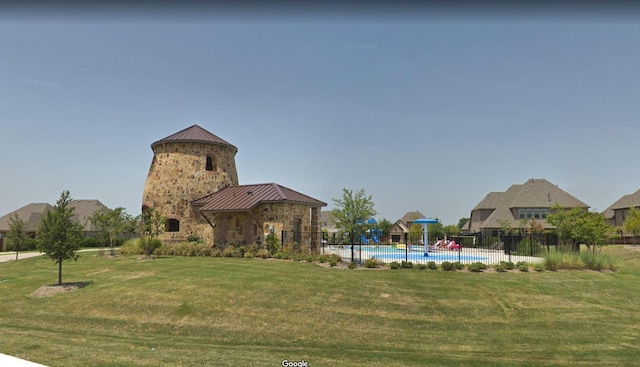 view of community featuring a swimming pool, a yard, and fence