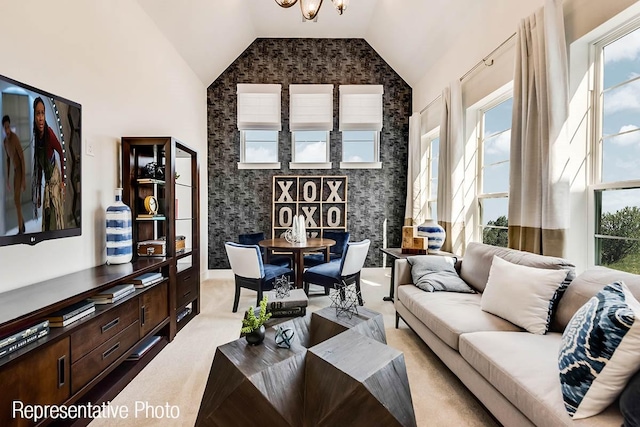 carpeted living room featuring a notable chandelier and high vaulted ceiling