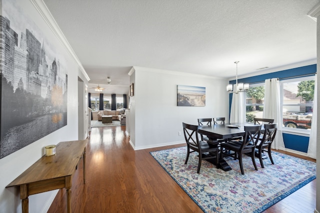 dining area featuring hardwood / wood-style flooring, ceiling fan with notable chandelier, ornamental molding, and a textured ceiling