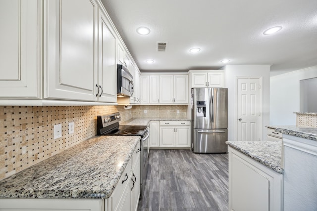 kitchen featuring white cabinetry, stainless steel appliances, light stone counters, dark hardwood / wood-style flooring, and decorative backsplash