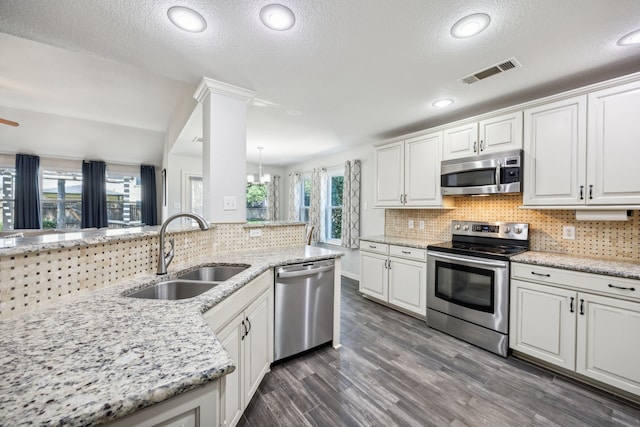 kitchen with sink, appliances with stainless steel finishes, dark hardwood / wood-style flooring, white cabinets, and backsplash