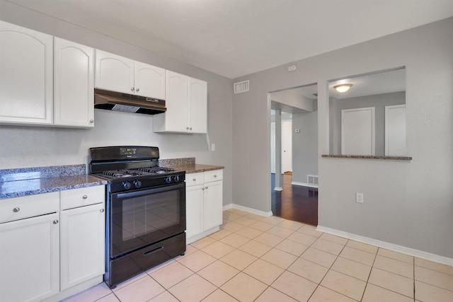 kitchen featuring light tile patterned flooring, dark stone countertops, white cabinets, and black gas range