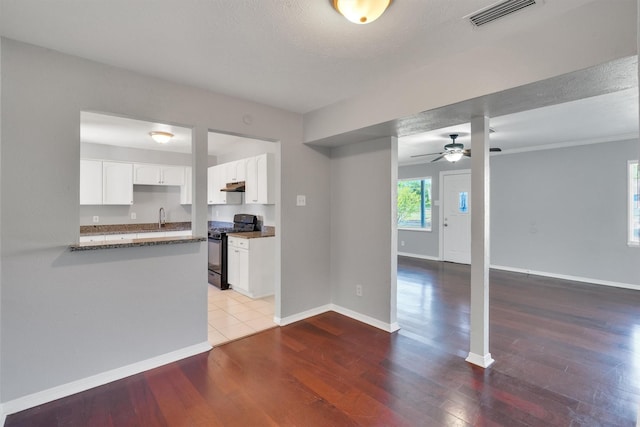 unfurnished living room featuring hardwood / wood-style flooring, ceiling fan, sink, and a textured ceiling