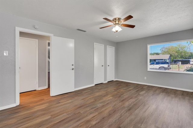 unfurnished bedroom with dark wood-type flooring, ceiling fan, and a textured ceiling