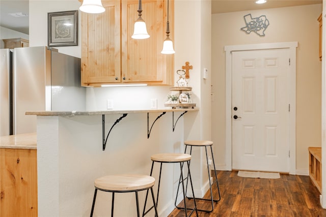 kitchen with a breakfast bar, pendant lighting, light brown cabinets, and kitchen peninsula