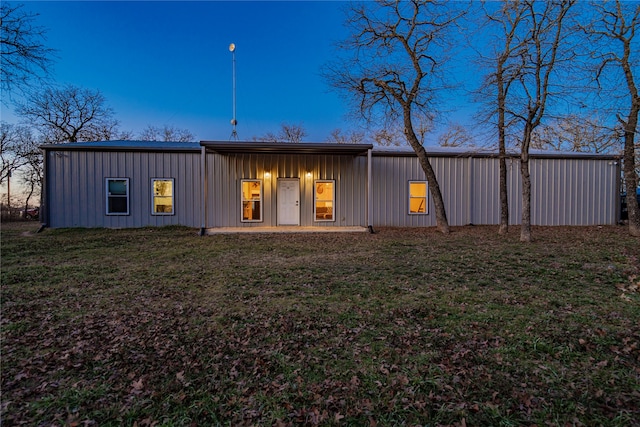 back house at dusk featuring a yard