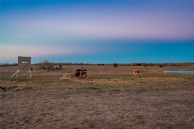 yard at dusk featuring a rural view