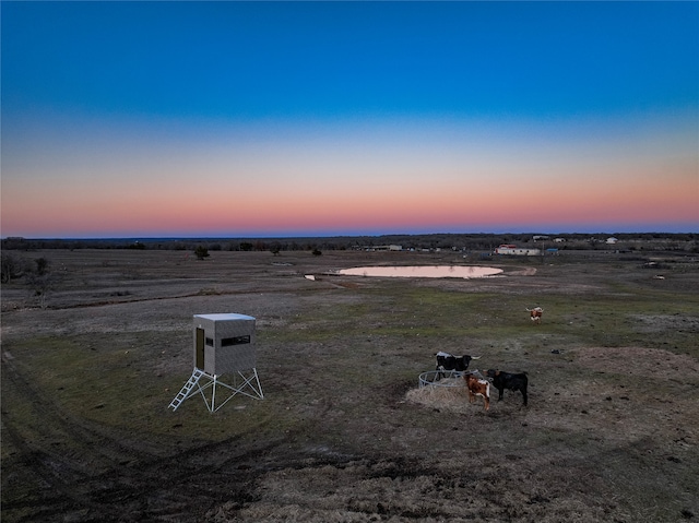 aerial view at dusk featuring a water view and a rural view