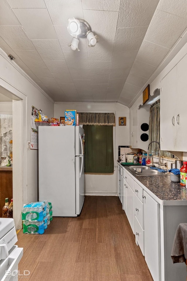 kitchen with white refrigerator, white cabinetry, sink, and light hardwood / wood-style flooring