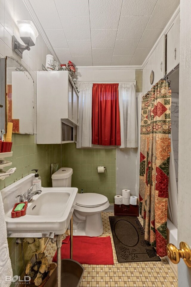 full bathroom featuring sink, shower / tub combo, tile walls, ornamental molding, and toilet