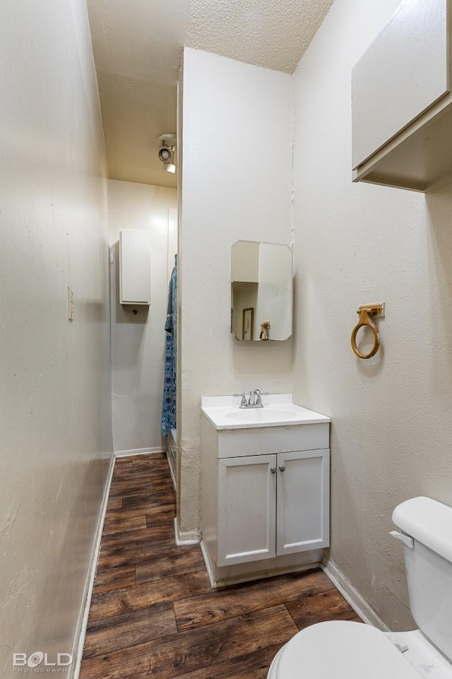 bathroom featuring vanity, hardwood / wood-style flooring, a textured ceiling, and toilet