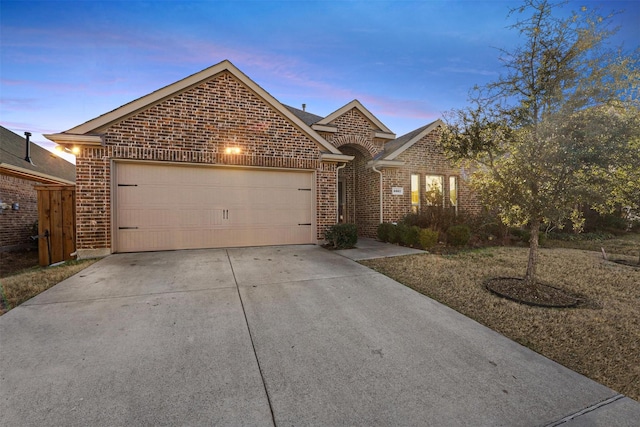 single story home featuring driveway, brick siding, and an attached garage