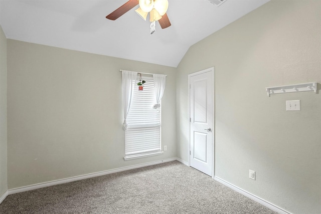 empty room with lofted ceiling, ceiling fan, carpet floors, visible vents, and baseboards