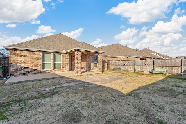 rear view of property featuring a patio, brick siding, and fence