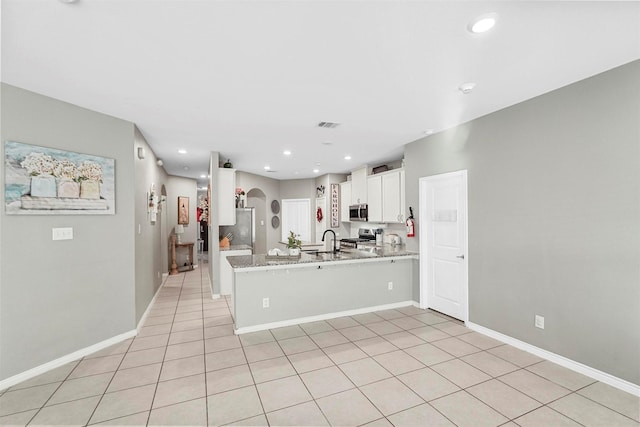 kitchen featuring light stone counters, arched walkways, appliances with stainless steel finishes, white cabinets, and a peninsula