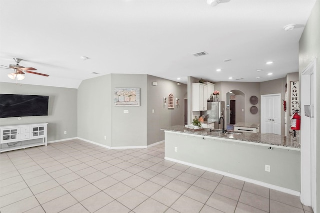 kitchen with arched walkways, light tile patterned floors, a sink, visible vents, and freestanding refrigerator