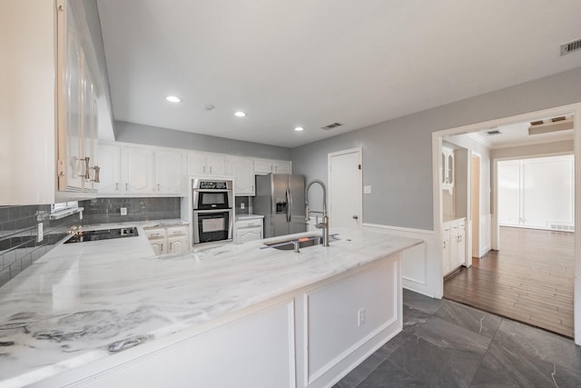 kitchen featuring sink, white cabinetry, appliances with stainless steel finishes, kitchen peninsula, and backsplash