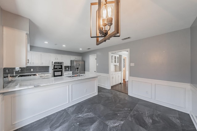 kitchen featuring sink, white cabinetry, appliances with stainless steel finishes, kitchen peninsula, and decorative backsplash