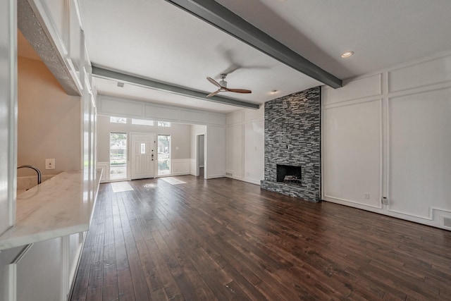 unfurnished living room featuring beamed ceiling, dark hardwood / wood-style flooring, ceiling fan, and a fireplace