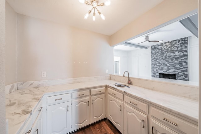 kitchen featuring sink, dark hardwood / wood-style flooring, beamed ceiling, ceiling fan with notable chandelier, and white cabinets