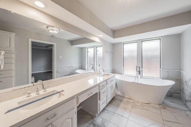 bathroom featuring vanity, a bath, and tile walls