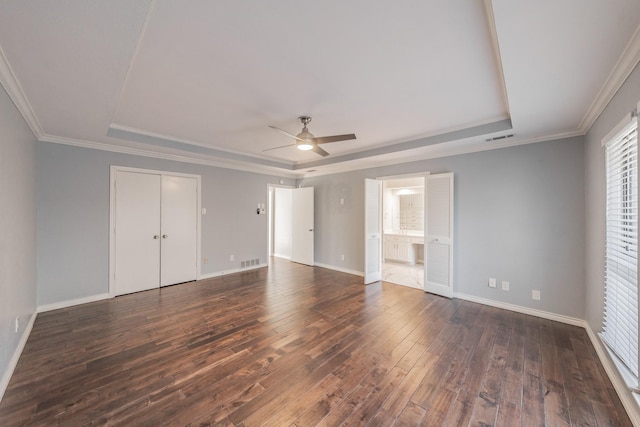 unfurnished bedroom featuring ceiling fan, connected bathroom, ornamental molding, dark hardwood / wood-style flooring, and a raised ceiling