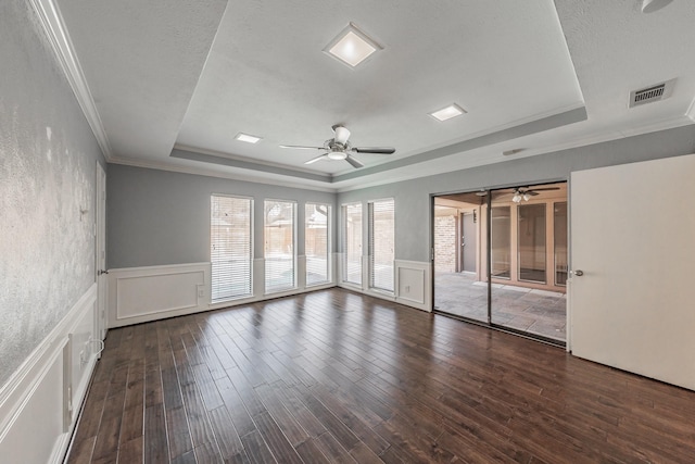 unfurnished room featuring crown molding, ceiling fan, a textured ceiling, dark hardwood / wood-style flooring, and a raised ceiling