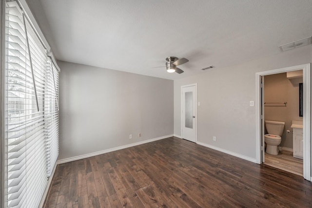 unfurnished bedroom featuring ceiling fan, dark wood-type flooring, and ensuite bath