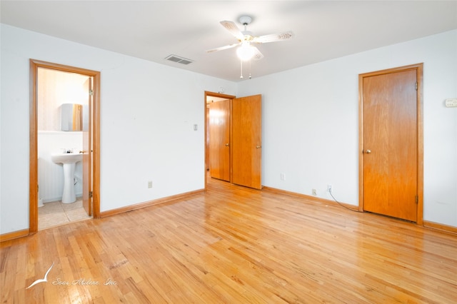 unfurnished bedroom with ensuite bathroom, sink, and light hardwood / wood-style floors