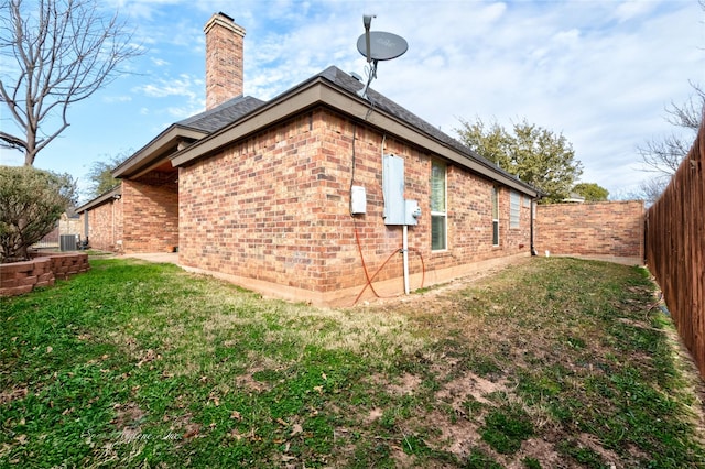 view of side of home featuring central AC unit and a lawn