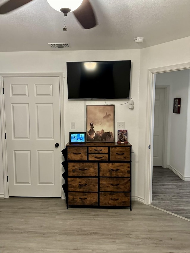 bedroom with ceiling fan, a textured ceiling, and light wood-type flooring