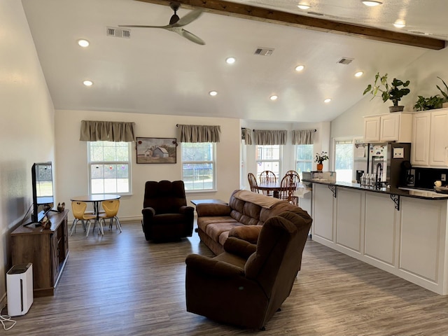 living room with vaulted ceiling with beams, wood-type flooring, and a healthy amount of sunlight