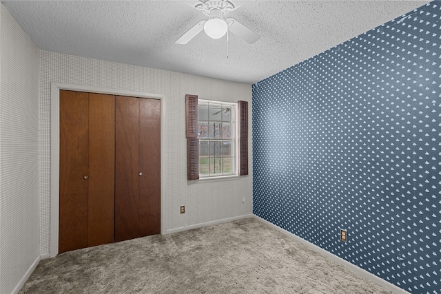 unfurnished bedroom with ceiling fan, light colored carpet, a closet, and a textured ceiling