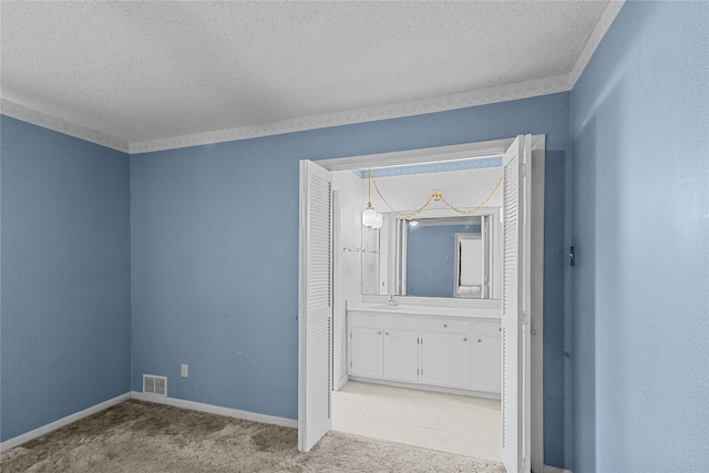 unfurnished room featuring ornamental molding, sink, light carpet, and a textured ceiling