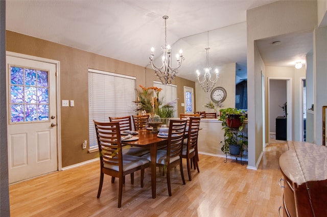 dining room featuring lofted ceiling, light hardwood / wood-style flooring, and a notable chandelier