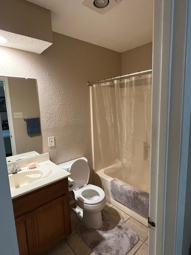 bathroom with vanity, shower / bathtub combination with curtain, tile patterned floors, toilet, and a textured wall