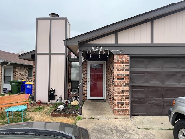 view of exterior entry with brick siding and a garage