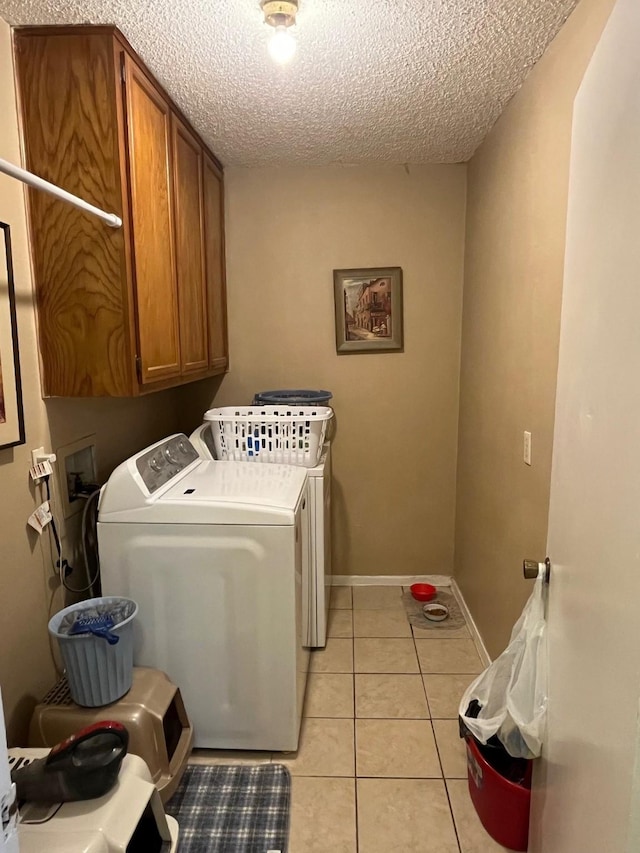 laundry area featuring cabinets, washing machine and dryer, light tile patterned flooring, and a textured ceiling