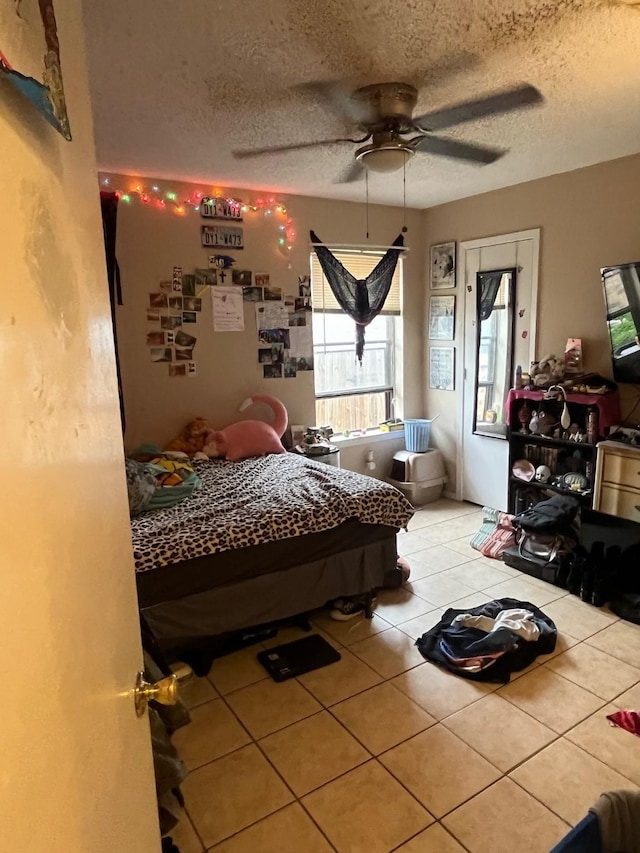 tiled bedroom with ceiling fan and a textured ceiling