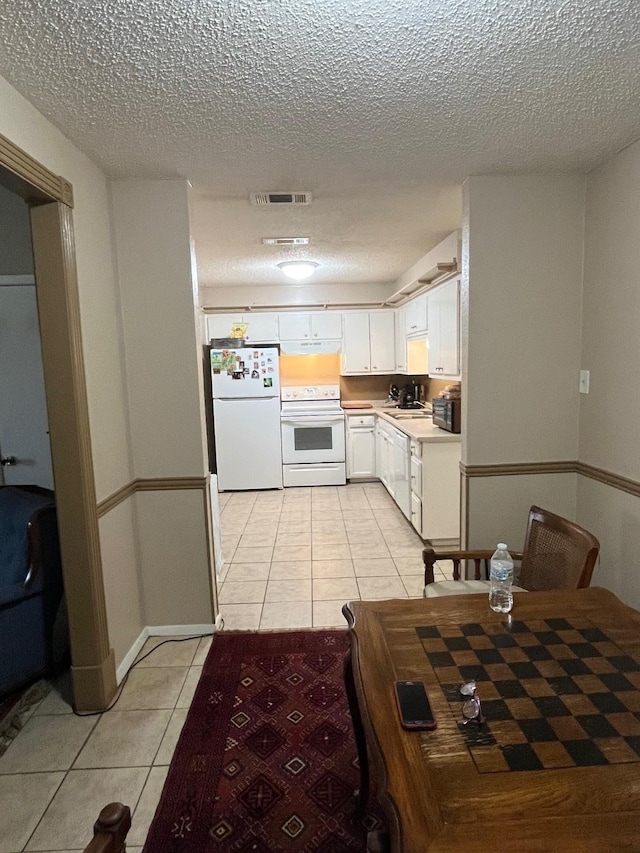 kitchen with white appliances, light tile patterned floors, visible vents, light countertops, and white cabinetry