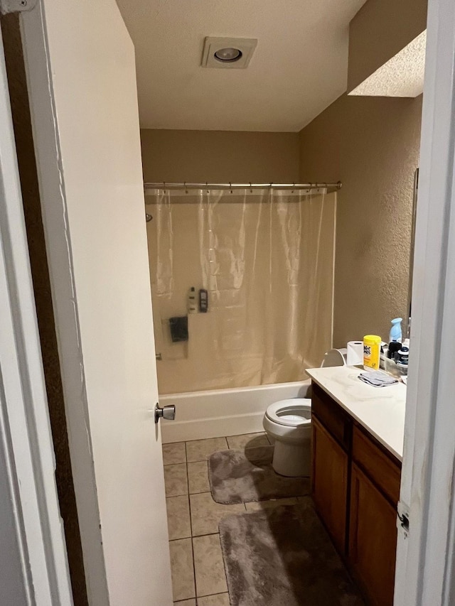 bathroom featuring tile patterned flooring, toilet, a textured wall, shower / bath combination with curtain, and vanity