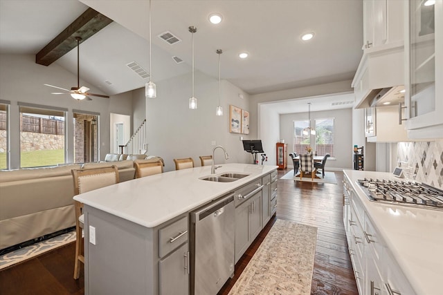 kitchen featuring sink, a kitchen bar, stainless steel appliances, and a center island with sink