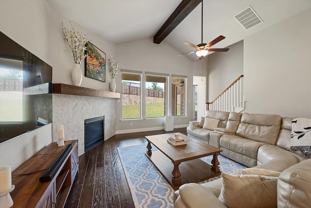 living room with high vaulted ceiling, beamed ceiling, a tiled fireplace, ceiling fan, and dark wood-type flooring