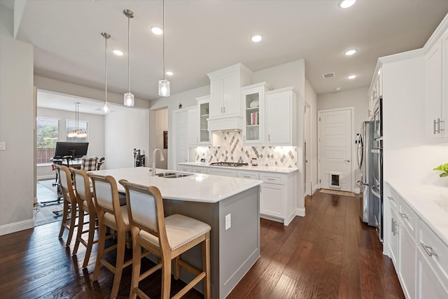 kitchen featuring pendant lighting, sink, white cabinetry, a kitchen island with sink, and stainless steel gas cooktop