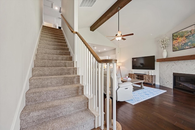 staircase with hardwood / wood-style flooring, ceiling fan, a fireplace, and lofted ceiling with beams