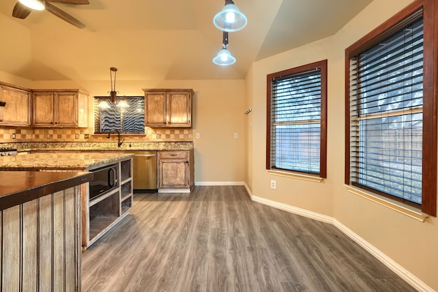 kitchen with vaulted ceiling, hanging light fixtures, dark hardwood / wood-style floors, light stone countertops, and decorative backsplash