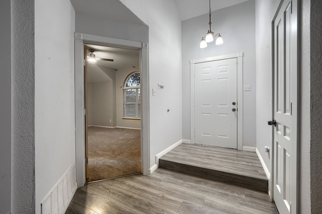 foyer entrance featuring ceiling fan with notable chandelier and hardwood / wood-style floors