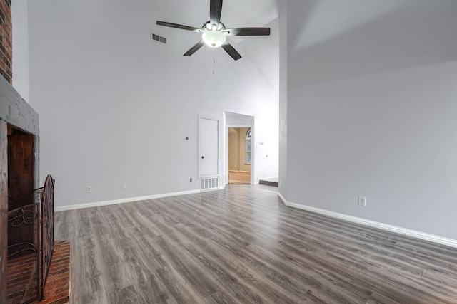 unfurnished living room with dark wood-type flooring, ceiling fan, and a high ceiling