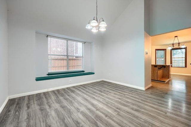 spare room with high vaulted ceiling, a chandelier, and hardwood / wood-style floors